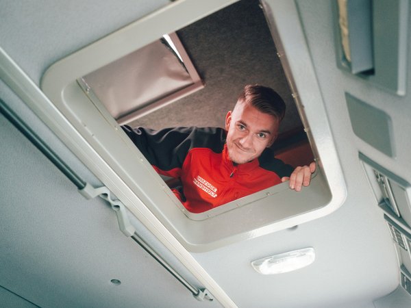 Person blickt von Schlafraum in Fahrer:innengastraum und lächelt