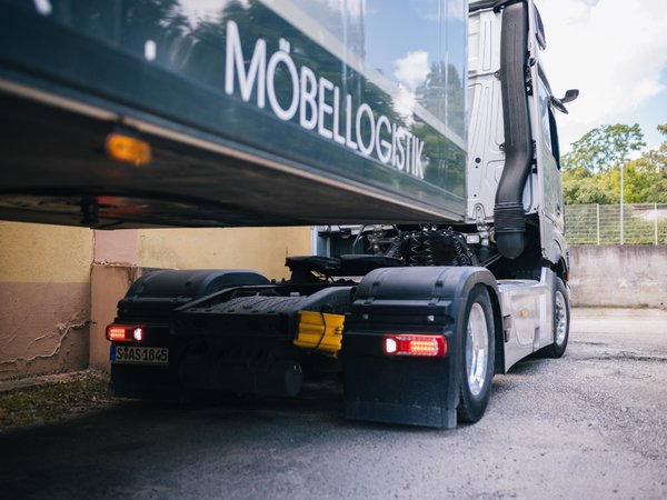 LKW mit Anhänger und Beschriftung Möbellogistik