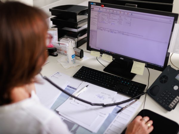 Person am Telefon mit Blick in einen Computer